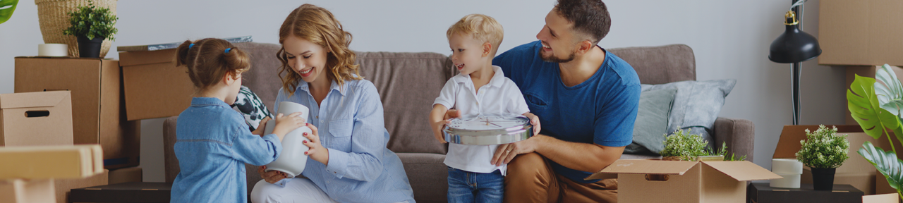 Family Smiling While Unpacking Boxes from Move