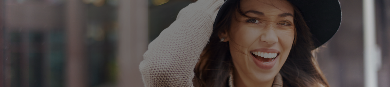 Woman Smiling While Holding Hat on Windy Day