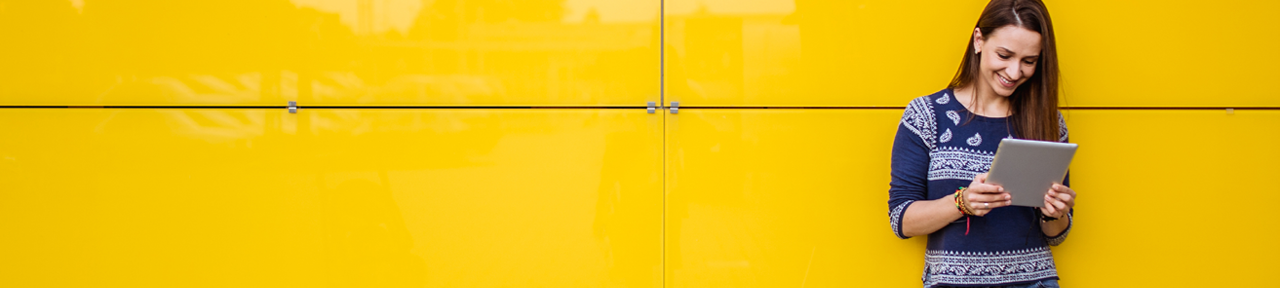 Woman Using Mobile Banking Leaning Against Yellow Wall