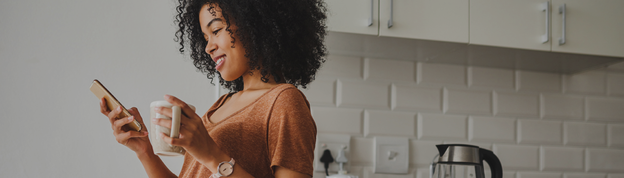 Woman Holding Coffee and Browsing Chequing Accounts on Phone