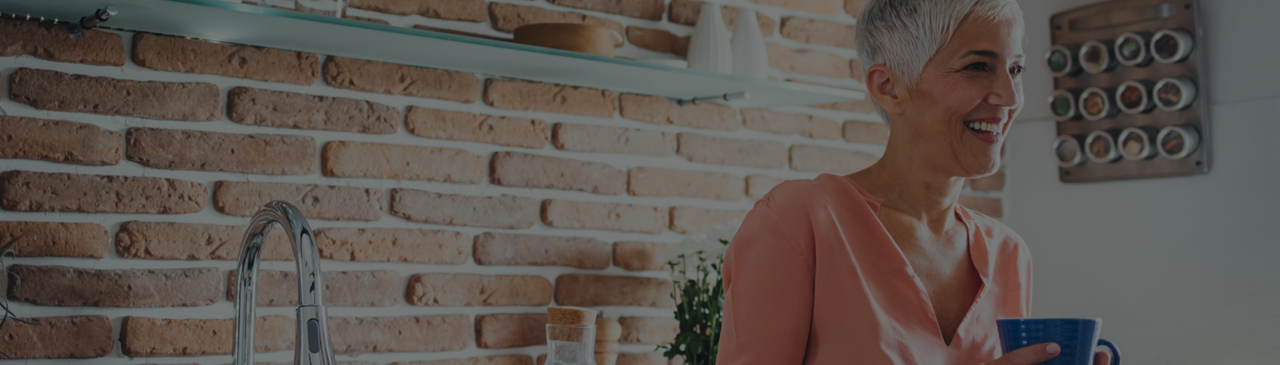 Woman Holding Coffee Cup and Smiling while Standing in Kitchen