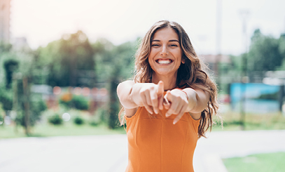 Woman Smiling and Pointing at the Camera