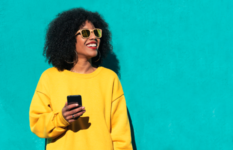 Woman Smiling in the Sunshine While Banking on Mobile Phone