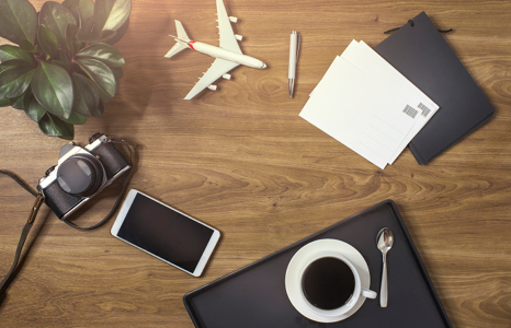 Coffee, Phone, Camera and Other Travel Essentials on Desk