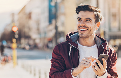 Man Smiling While Using Mobile Phone Outside