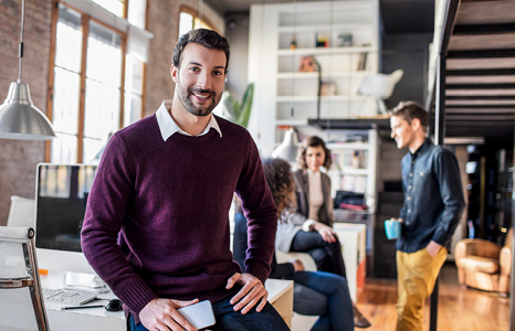 Man Smiling and Leaning on Desk in Office Space