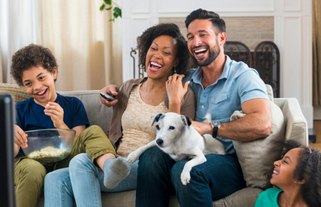 Family Laughing on Couch with Small White Dog
