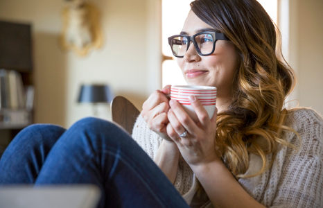 Woman Smiling and Enjoying Cup of Coffee in Living Room