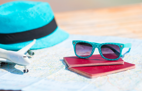 Sunglasses, Passports and Map on Table with Blue Hat and Toy Plane