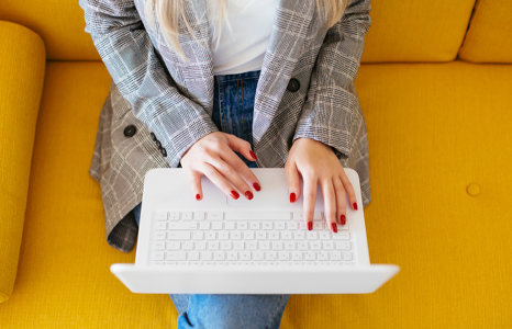 Woman Using Online Banking to Pay Bills Sitting on Yellow Couch