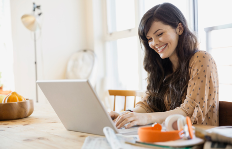 Woman Smiling at Computer While Using Online Banking