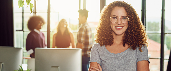 Woman Smiling Cross Armed Leaning on Desk in Office