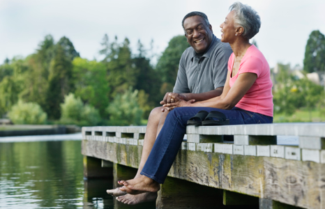 Couple Smiling at Each Other While Sitting on Bridge