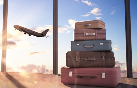 Stack of Four Suitcases in Front of Window with Plane Ascending