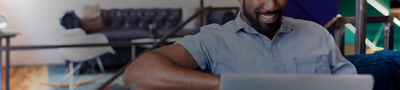 Man Sitting on Couch Browsing FirstOntario Business Products on Laptop