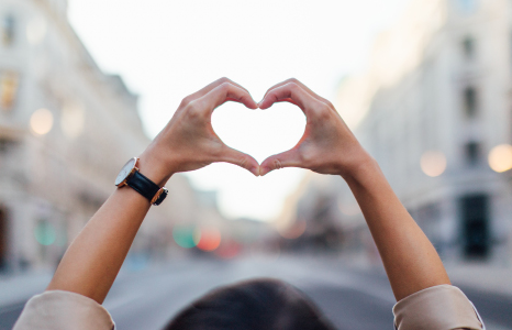 Person Standing in Street Forming Heart with Hands