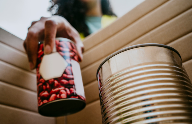 Person Putting Canned Goods in a Box