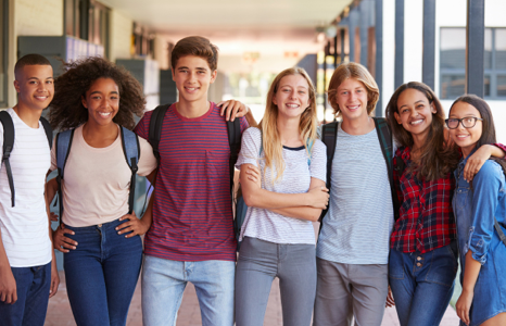 Group of young people smiling with arms around each other