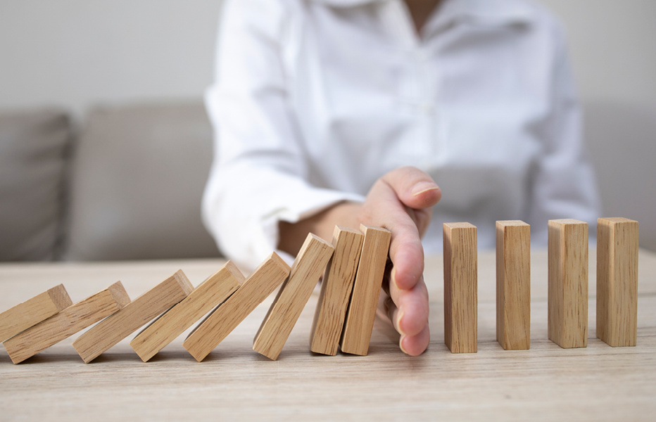 Person Preventing Wooden Dominoes From Falling