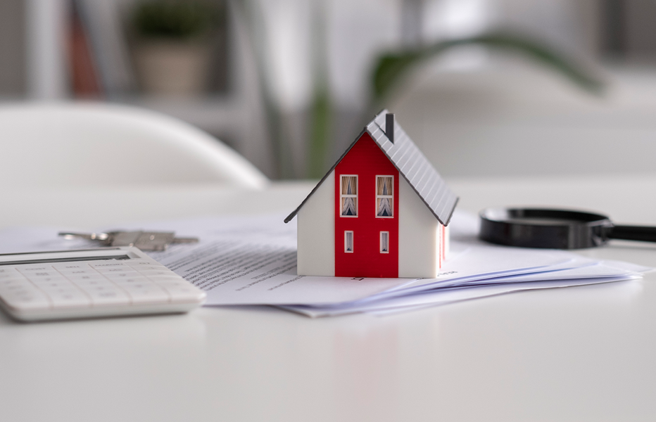 Small House Figurine on Pile of Papers