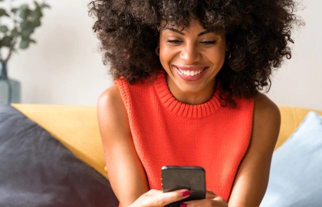 Woman in Orange Sweater Using FirstOntario Mobile App To Bank Online