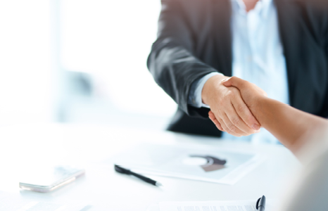 Two People Shaking Hands Over Signed Contract