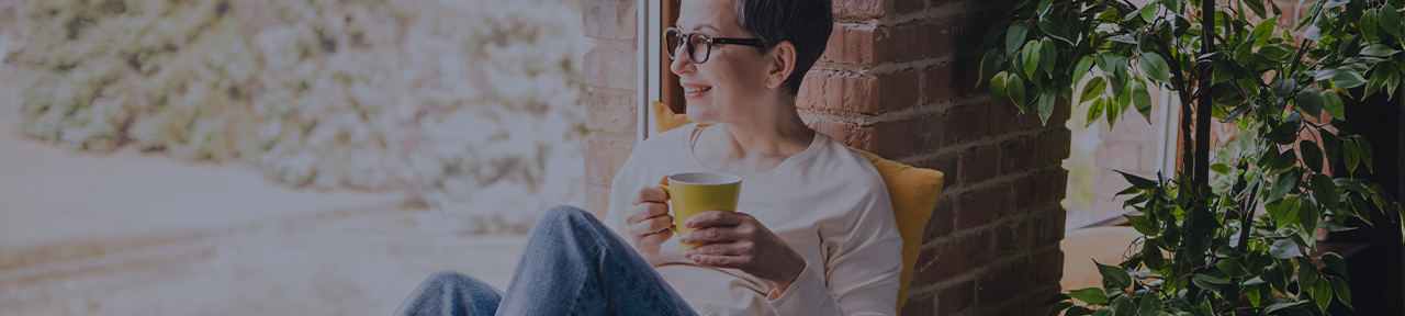 Woman holding a yellow mug while sitting on her porch