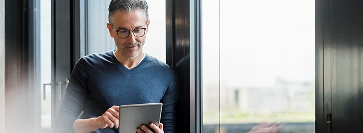 Man with glasses using tablet to learn about equity investments 
