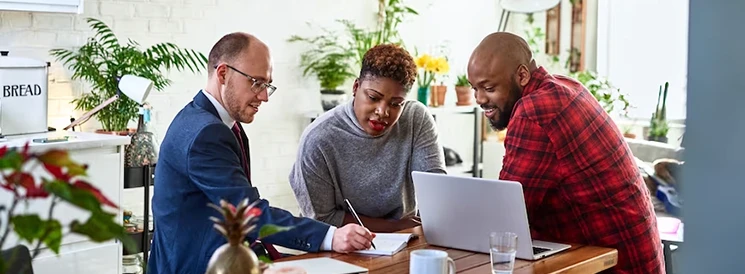 Couple meeting at kitchen table with financial advisor about GICs