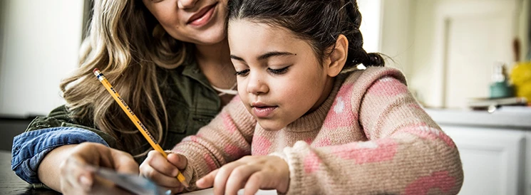 Mother and daughter working on homework at kitchen table