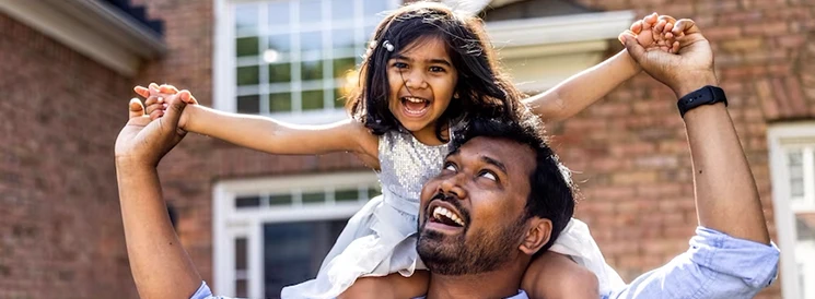 Daughter laughing while sitting on smiling father's shoulders 