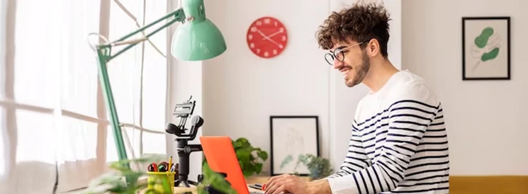 Young man with glasses and striped shirt filing tax return on laptop