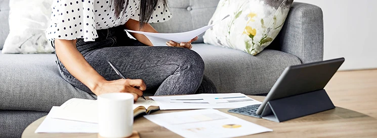 Person working on tablet and reviewing documents at a coffee table