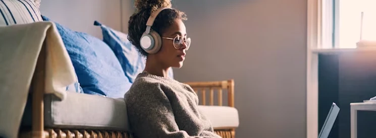 Young woman wearing headphones working on school work on laptop