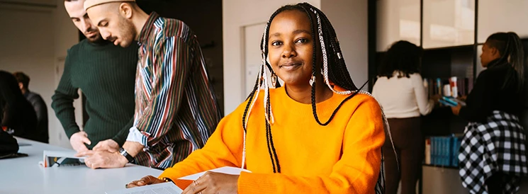 Woman in orange sweater working on school work in classroom