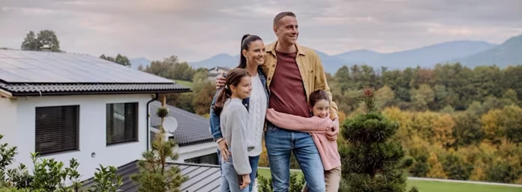 Family of four posing for picture in front of home