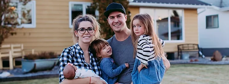 Family of five smiling in front of first home