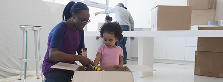 Mother and Daughter unpacking moving box in new kitchen