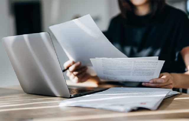 Person reviewing Insurance documents at wooden desk