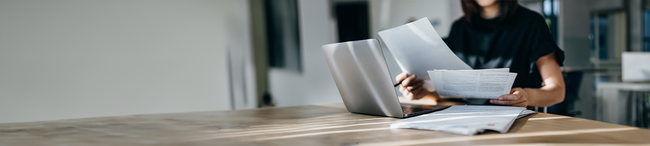 Woman working at laptop reviewing insurance paperwork