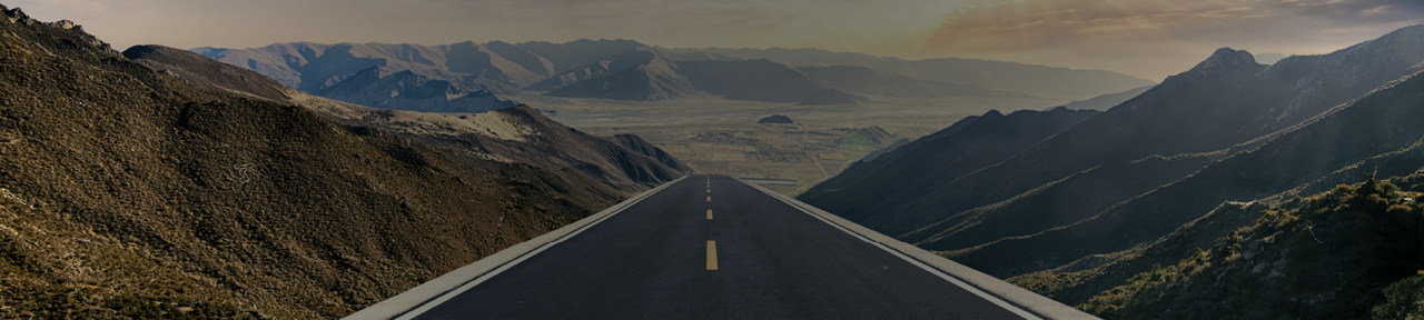 Open Road Through Mountains Disappearing into Horizon