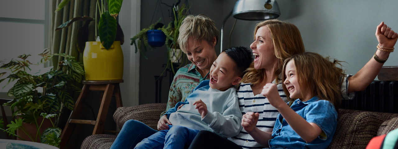 Family Sitting on Couch Cheering and Laughing