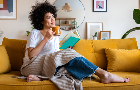 Woman Drinking Coffee on Couch with Tablet