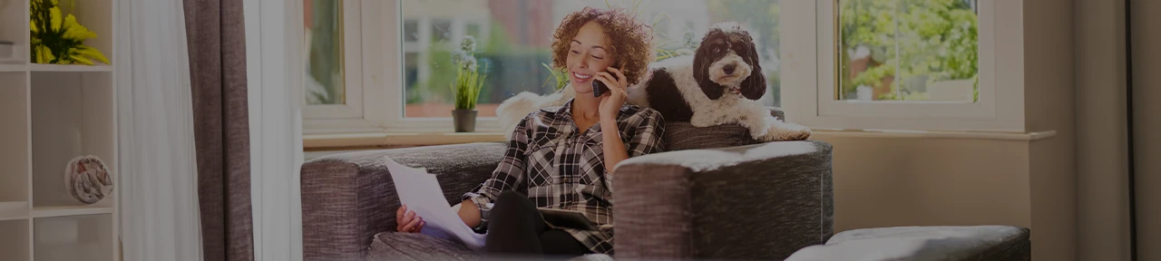 Woman Reviewing Mortgage Papers While Sitting with Dog on Couch