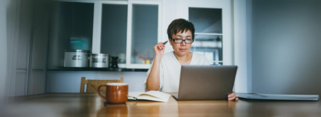 Woman sitting at computer at kitchen table