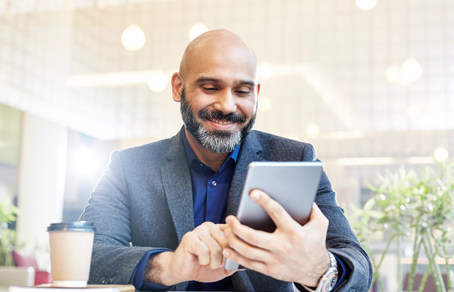 Man Smiling Using Small Tablet