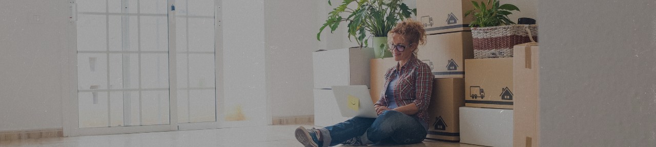 Woman sitting on the floor of new home using laptop