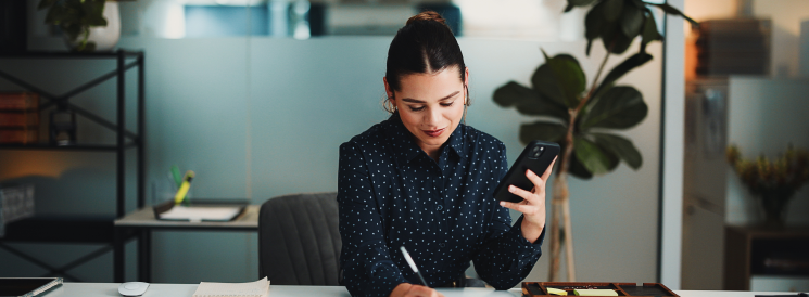 Woman taking notes while on call in private office