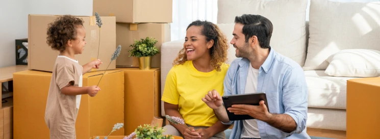 young family sitting on floor of new home with moving boxes