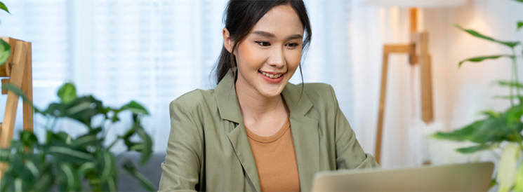 Woman in green blazer typing on laptop